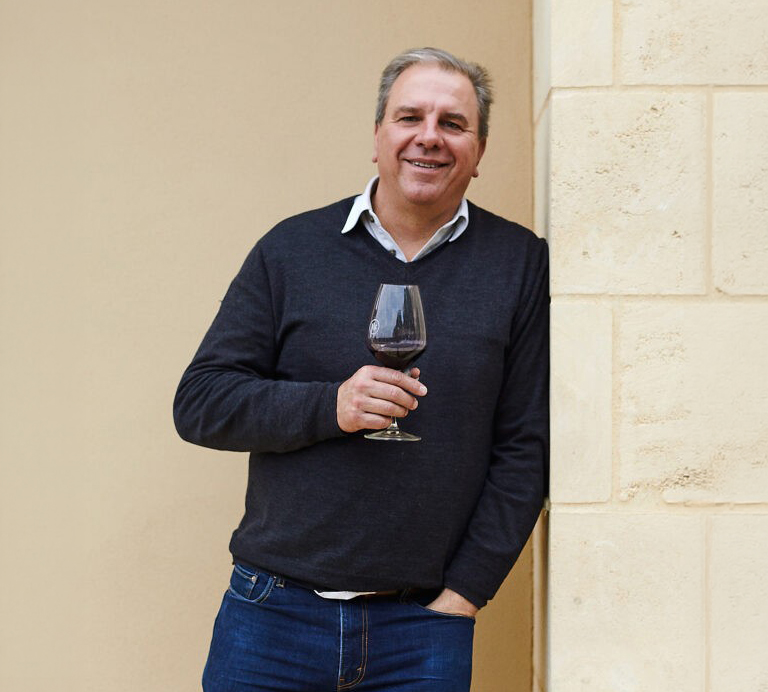 Winemaker tasting wine among oak barrels